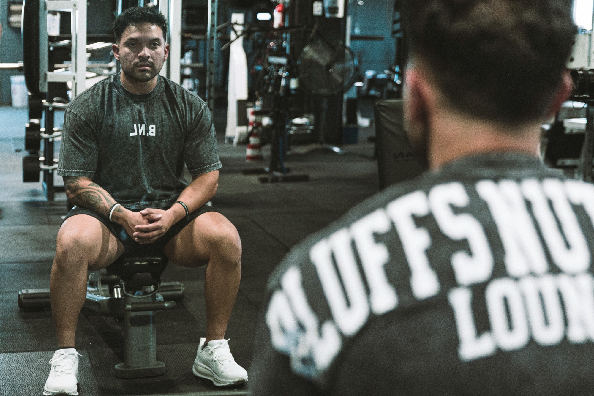 Elijah seated in the gym, facing his reflection in the mirror.