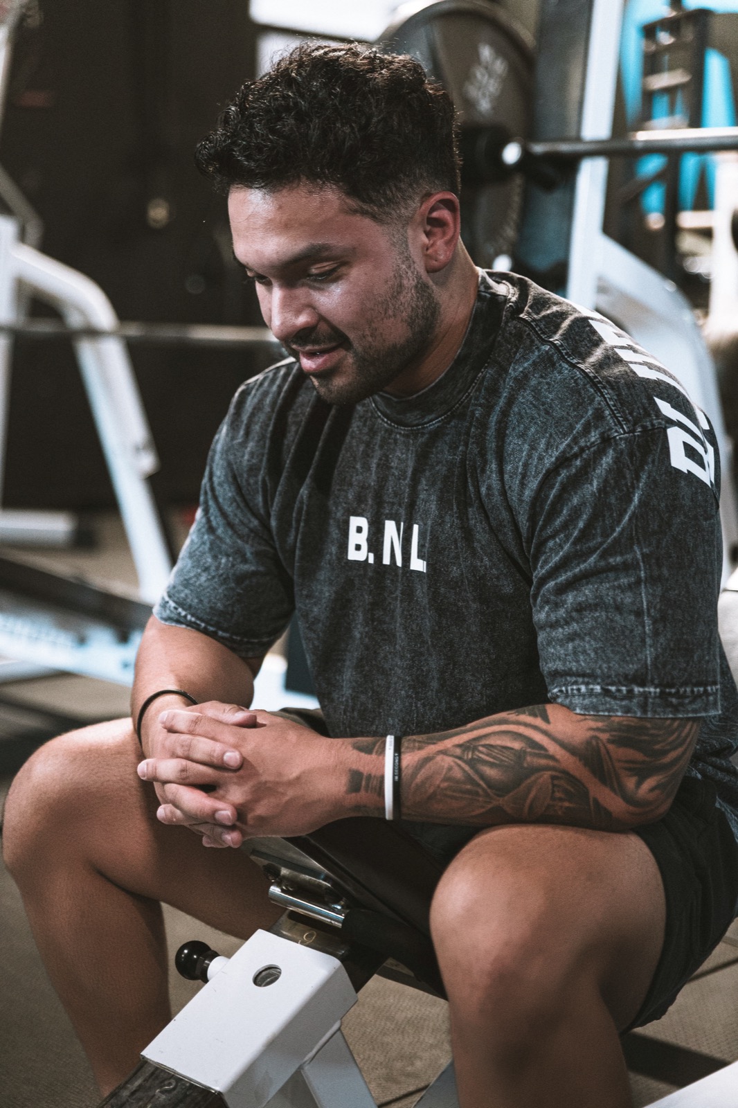 Elijah seated in the gym, hands clasped, smiling.